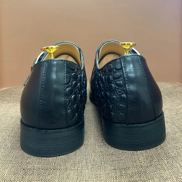 Black leather shoes with gold accents on a textured surface