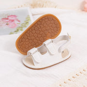 White sandal with brown sole on a textured white surface