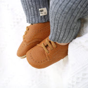 Brown baby shoes with a visible brand label on a white background