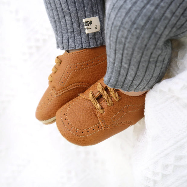 Brown baby shoes with a visible brand label on a white background