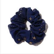 Navy blue scrunchie with gold star patterns on a white background