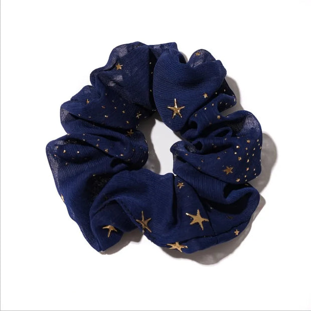Navy blue scrunchie with gold star patterns on a white background