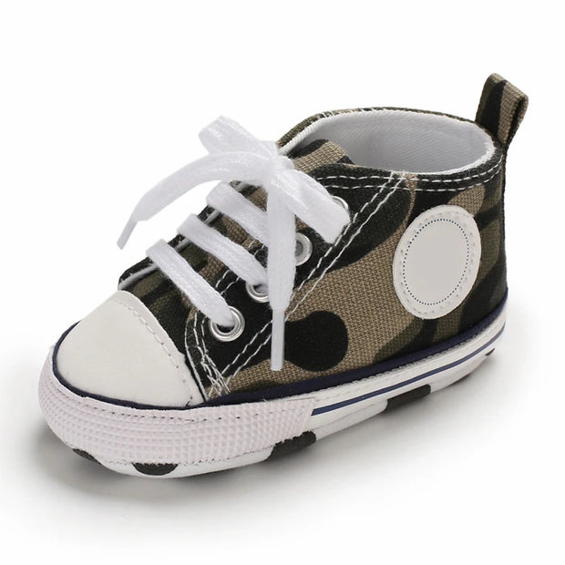 Camouflage-patterned baby shoe with white laces on a white background