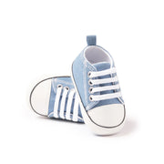 Pair of blue baby sneakers with white stripes on a white background