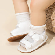 White sandals with brown soles worn by a child on a neutral background