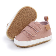 Pink baby shoes with velcro straps on a white background