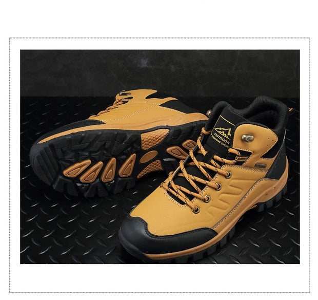 Pair of yellow hiking boots with black soles on a textured black background