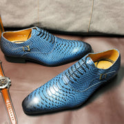 Blue textured dress shoes on a brown surface with a watch and belt visible.