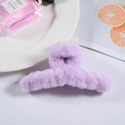 Purple fluffy hanger on a white surface with a pink product and white plate in the background.