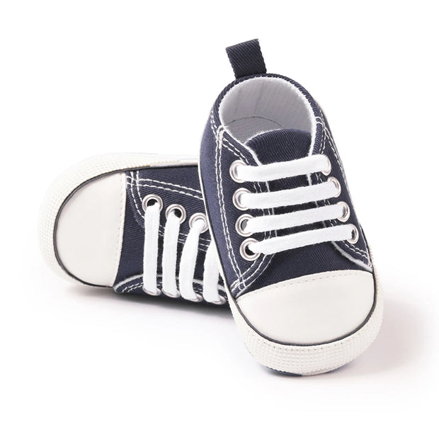 Navy blue baby sneakers with white soles on a white background