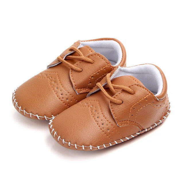Pair of brown baby shoes with white laces on a white background