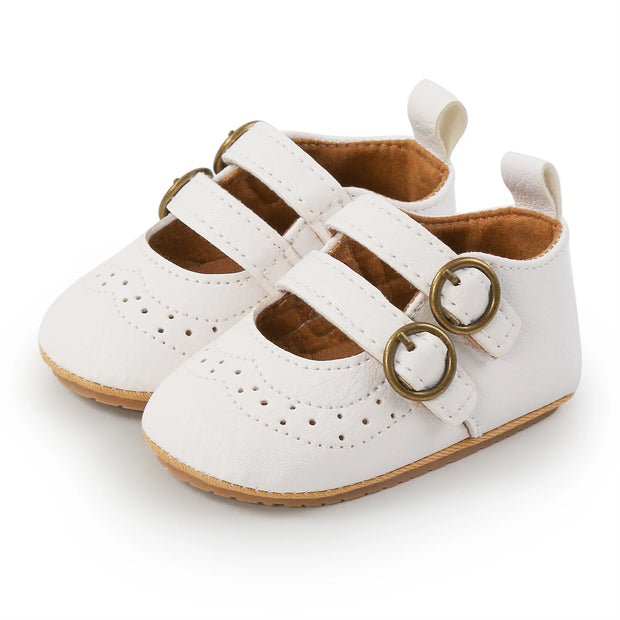 White baby shoes with gold buckles on a white background