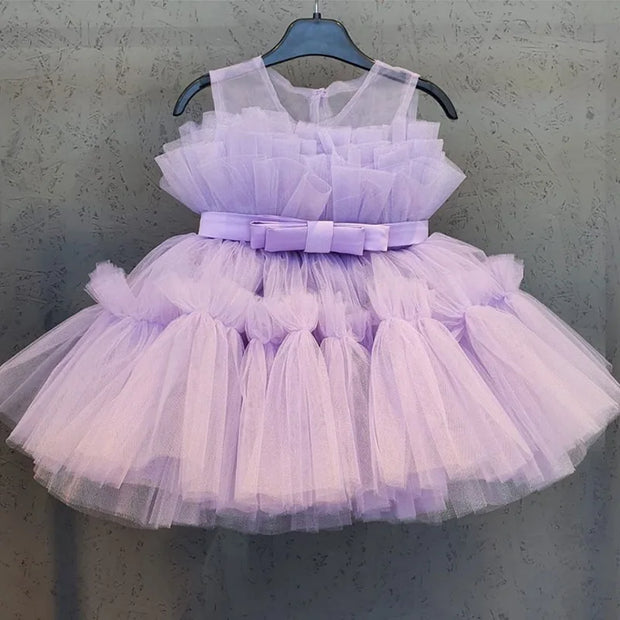 Lavender tulle dress with a bow on a hanger against a gray background