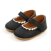 Black baby shoes with a strap on a white background