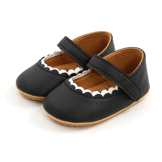 Black baby shoes with a strap on a white background