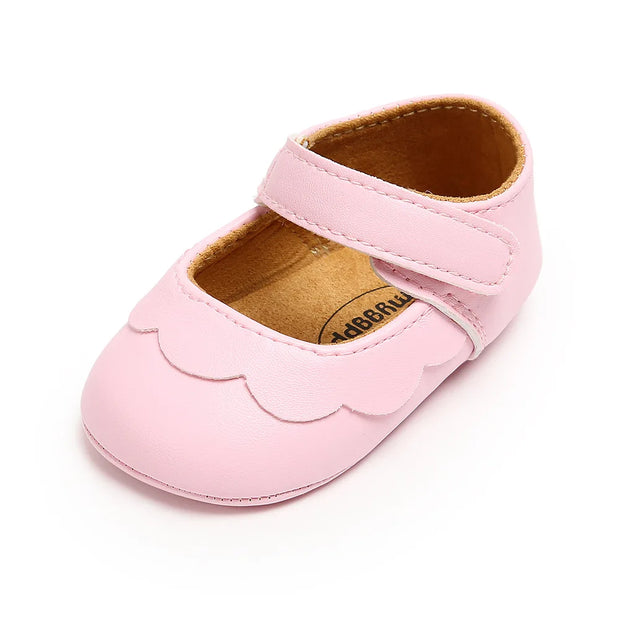 Pink baby shoe with scalloped edge on a white background