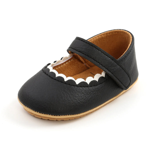 Black baby shoe with a strap on a white background