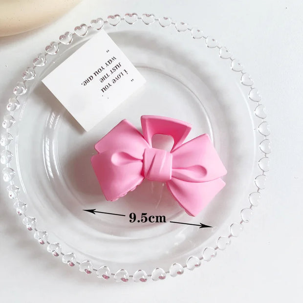 Pink bow hair clip on a decorative plate with measurement label