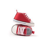 Red baby sneakers with white laces on a white background