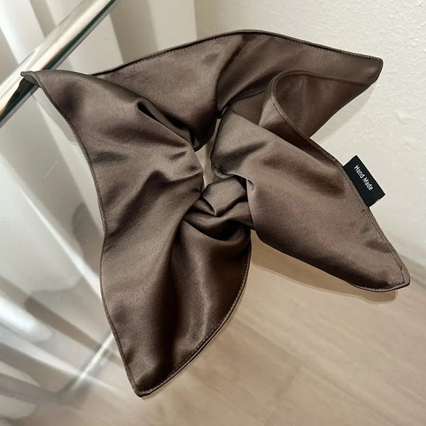 Brown satin scarf with a brand tag on a glass surface