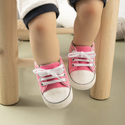 Child's feet wearing pink sneakers with white laces on a wooden stool.