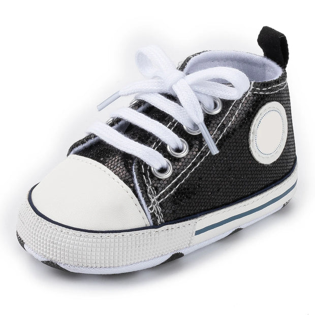 Black and white baby shoe with a white sole on a white background