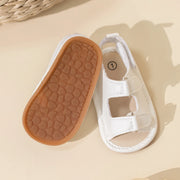 White baby shoe with brown sole on a beige background