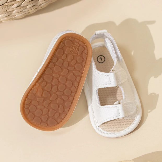 White baby shoe with brown sole on a beige background