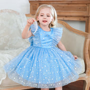 Young girl in a blue dress with star patterns sitting on a decorative chair.