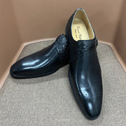Pair of black dress shoes on a textured surface with a neutral background