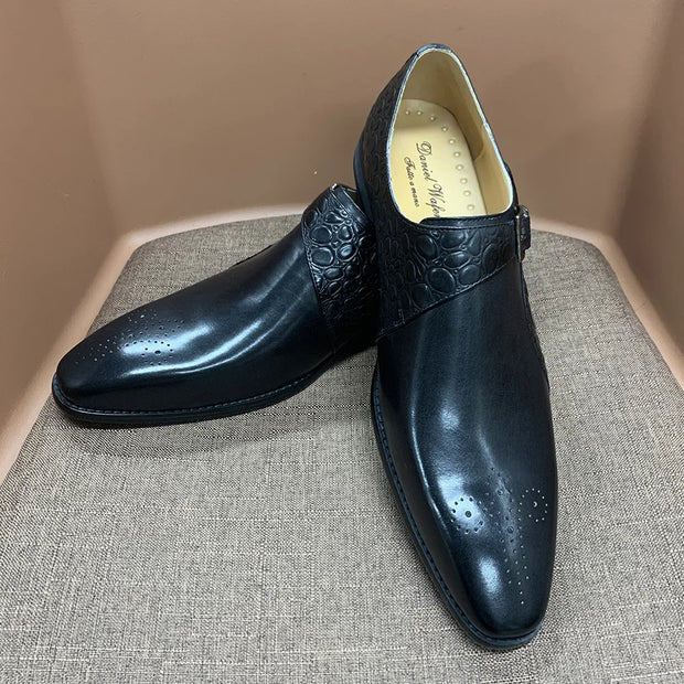 Pair of black dress shoes on a textured surface with a neutral background