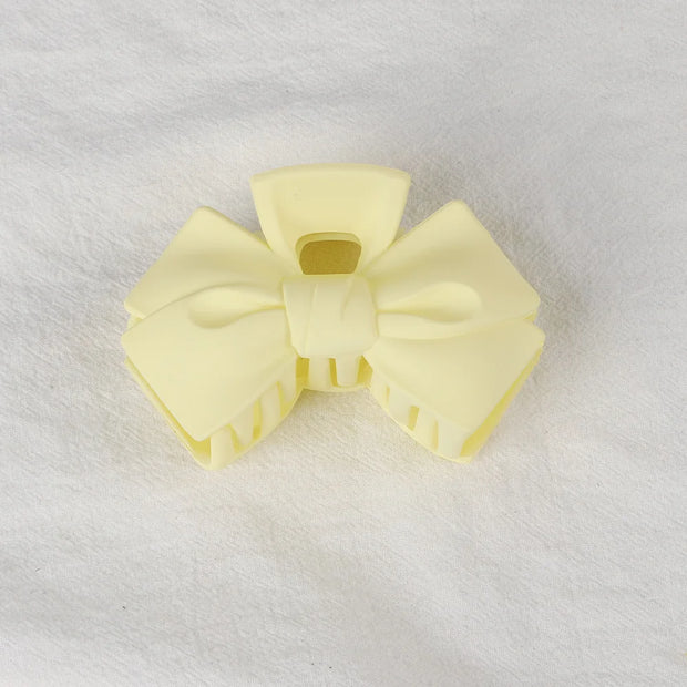 Pair of light yellow hair bows on a white background