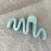 Light blue wavy hair clip on a gray surface
