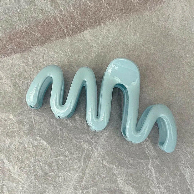 Light blue wavy hair clip on a gray surface