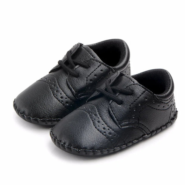 Pair of black leather baby shoes on a white background