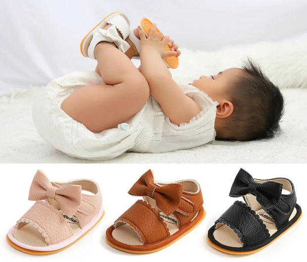 Baby lying on a white blanket with sandals displayed below