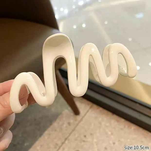 White silicone straw holder shaped like a snake held by a hand with a blurred background.