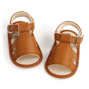 Pair of brown baby sandals with straps on a white background