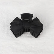 Black bow-shaped hair clip on a white textured background