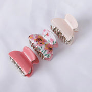 Two pink hair clips with floral design on a white background
