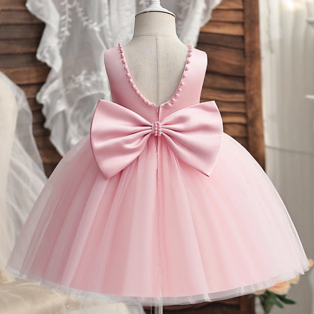 Pink dress with a large bow on a mannequin against a neutral background