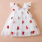 White dress with red cherry designs on a beige background