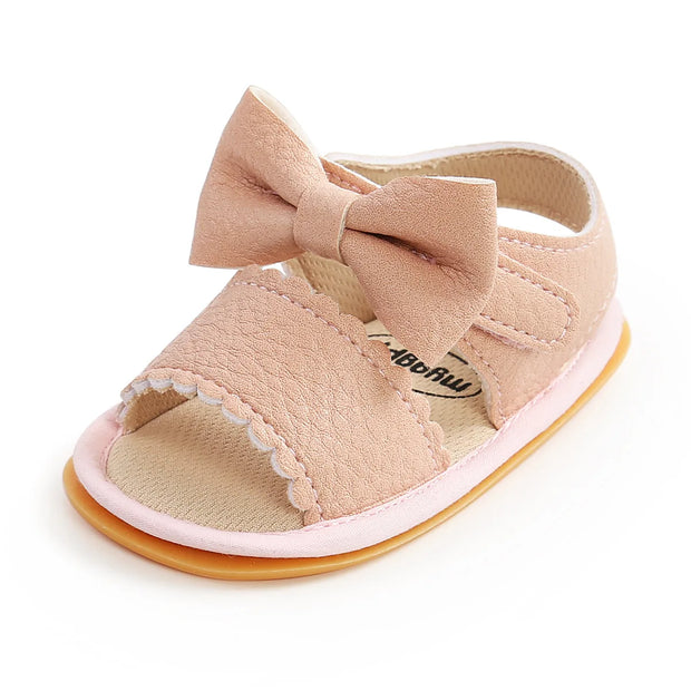 Pink baby sandal with a bow on a white background
