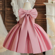 Pink dress with a large bow on a mannequin against a decorative background