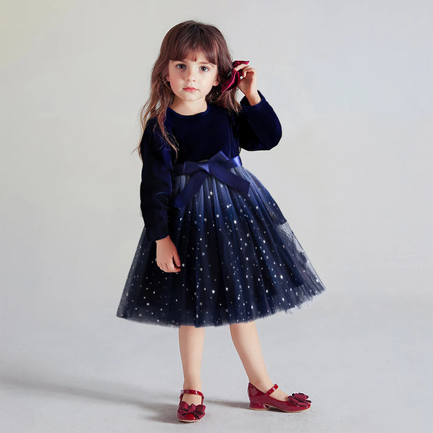 Young girl wearing a navy dress with a star-patterned skirt on a light gray background