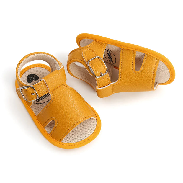 Pair of yellow baby sandals with buckles on a white background