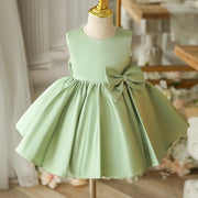 Light green dress with a bow on a mannequin against a blurred indoor background