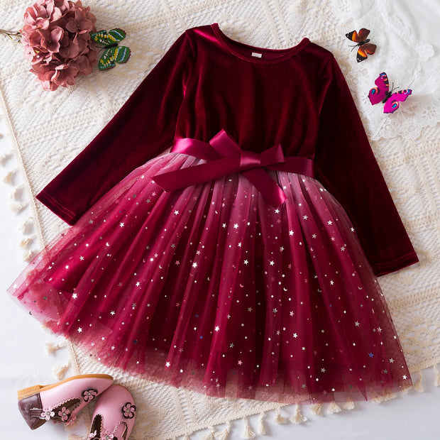 Burgundy dress with a star-patterned skirt on a textured surface with decorative elements.