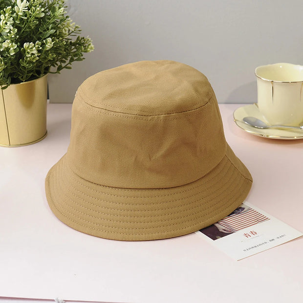 Beige bucket hat on a surface with a plant and cup in the background