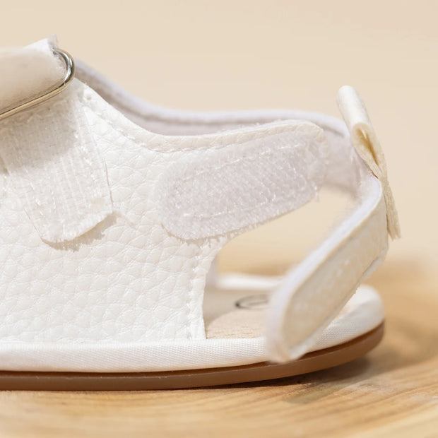 White sandal with a textured sole on a wooden surface